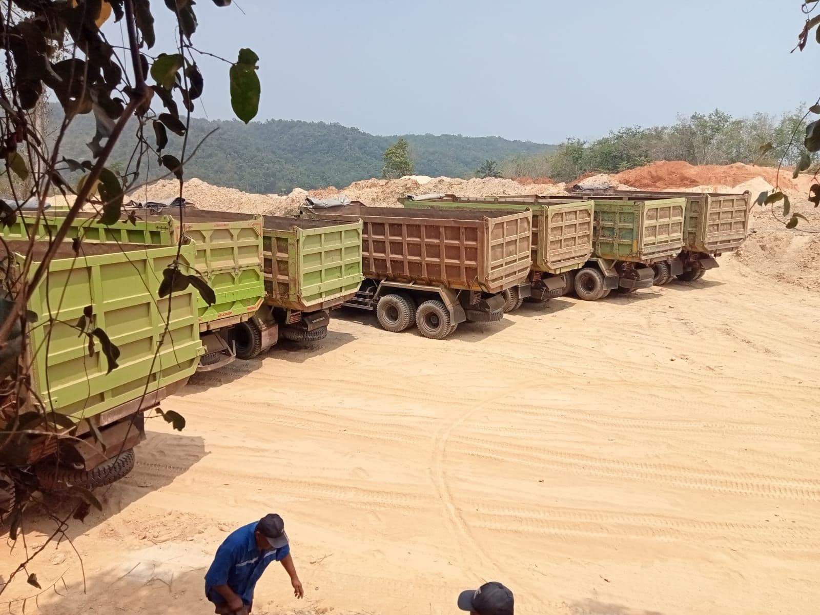 Deretan dump truck bermuatan material di lokasi sumber material